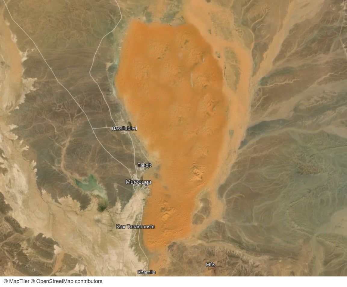 Satellite view of Erg Chebbi: an orange patch of sand sharply bounded on its western side by a road and the villages of Hassilabied, Merzouga and Khamlia
